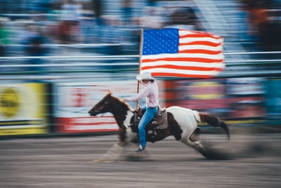 一名男子骑着棕色马背着美国国旗的延时照片